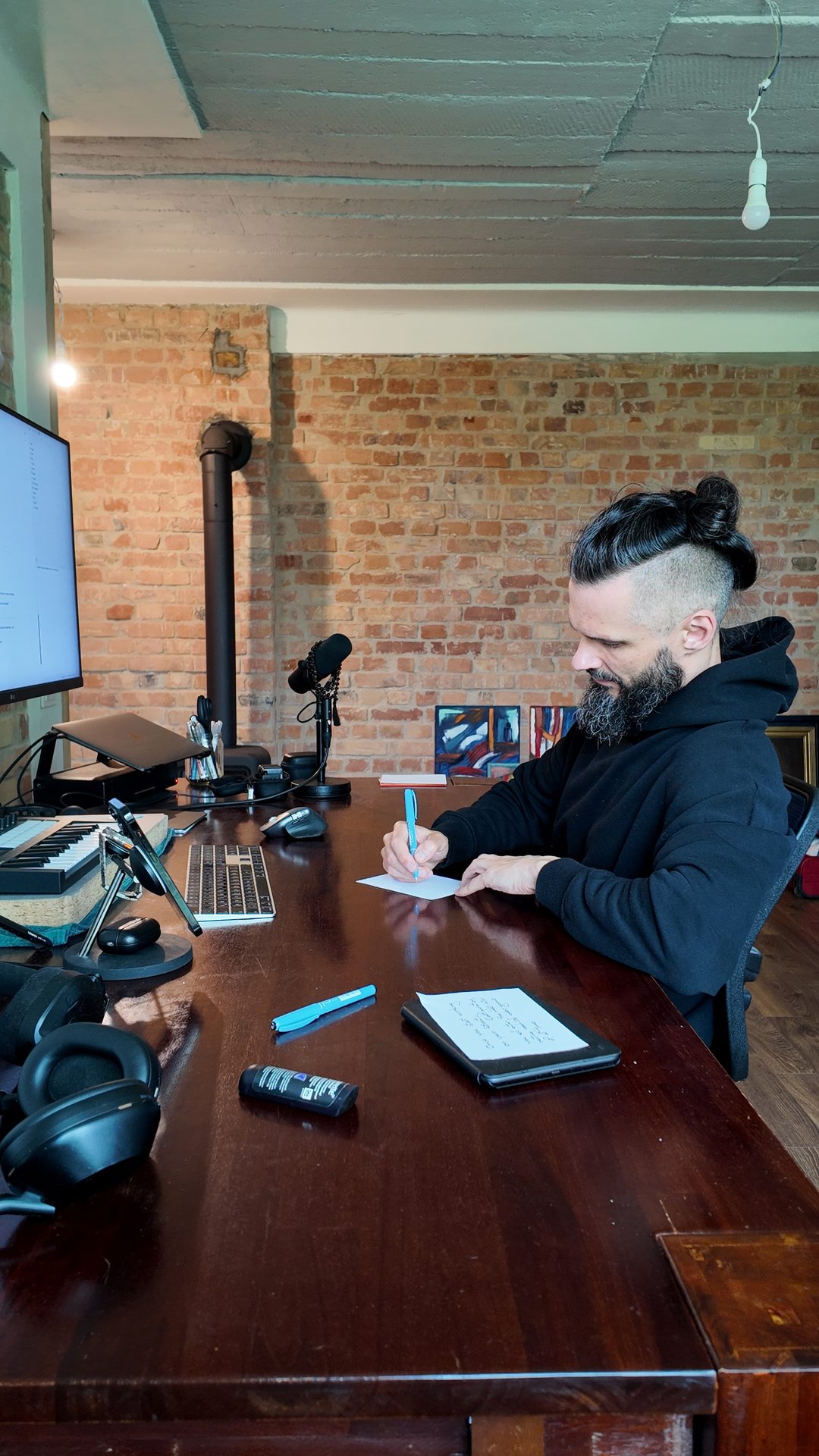 Lee writing in a notebook with a blue pen at the desk.