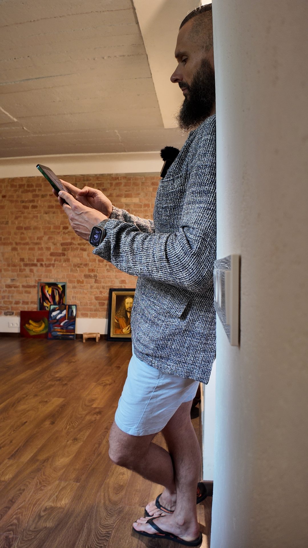 Lee standing against the wall, paintings leaning against the brick behind.