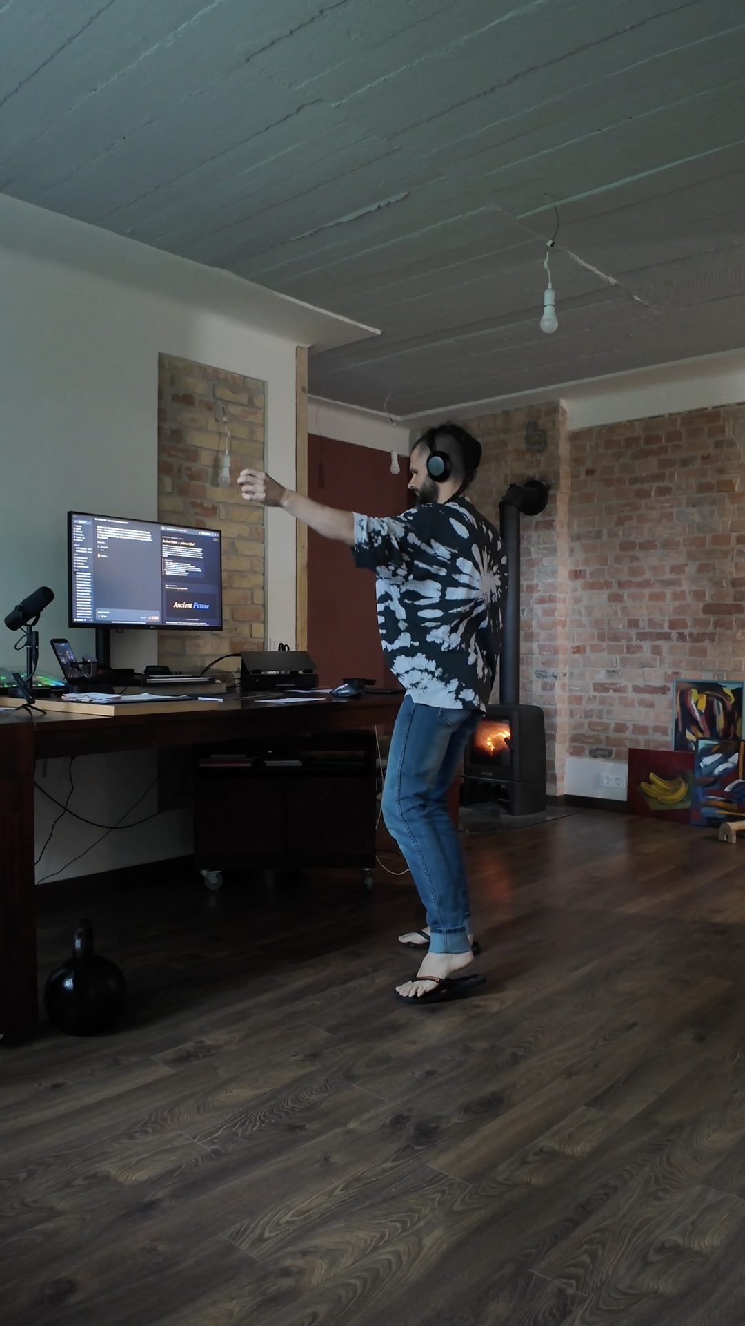 Lee dancing in the studio, headphones on, arm reaching, fire lit.